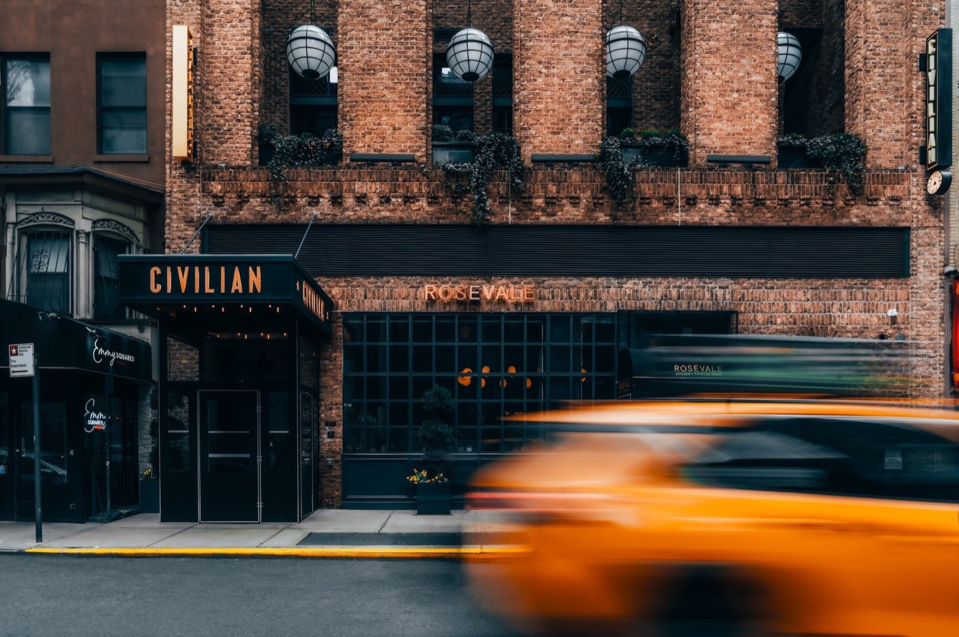 CIVILIAN's brick facade on West 48th Street, a yellow cab blurring past the entrance