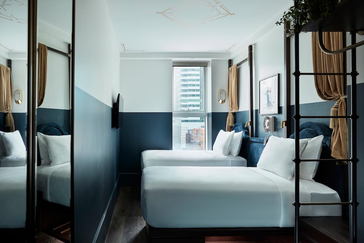 A Cozy Twin room: two twin beds with white linens, navy and white walls and a window at the far end