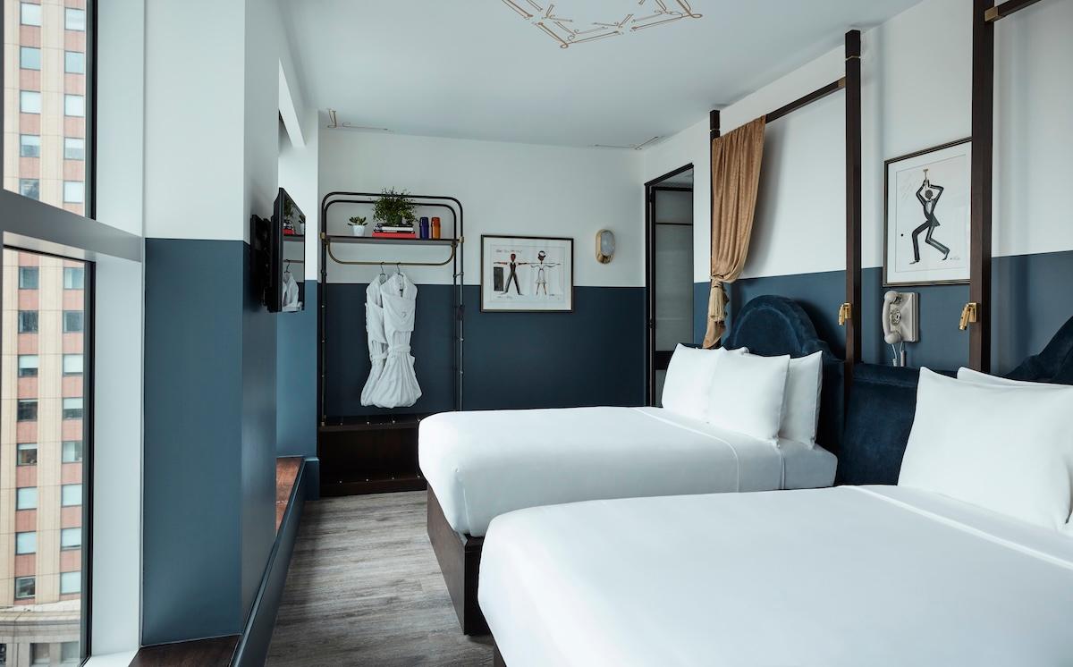 A Spacious Double Double room: two double beds with navy velvet headboards and an open rack with a robe