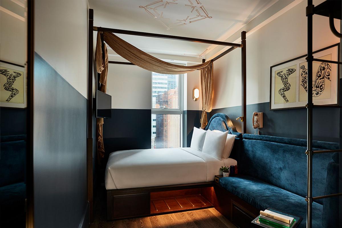 A Spacious Queen room: a four-poster queen bed with gold drapery beside a long navy velvet banquette